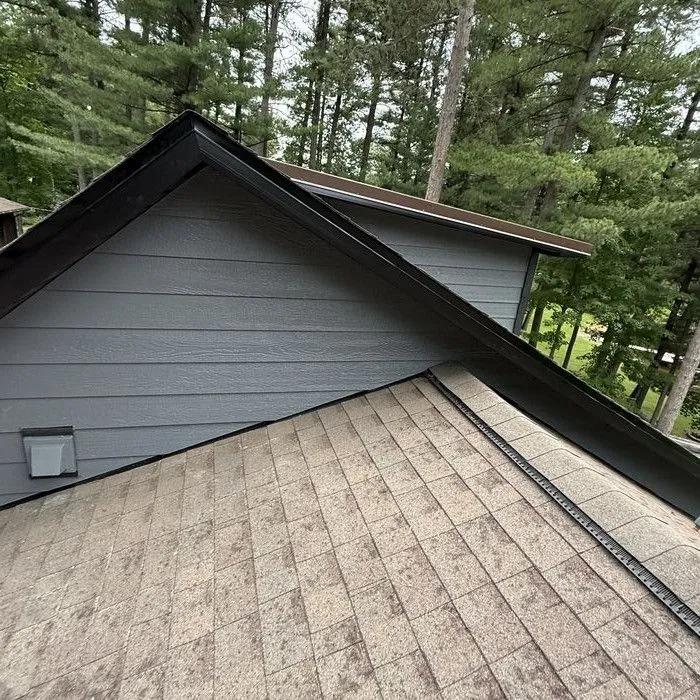 Dormer wall in new dark siding against the pines