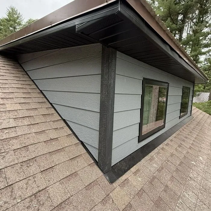 Dormer side wall in dark siding above the shingle roof