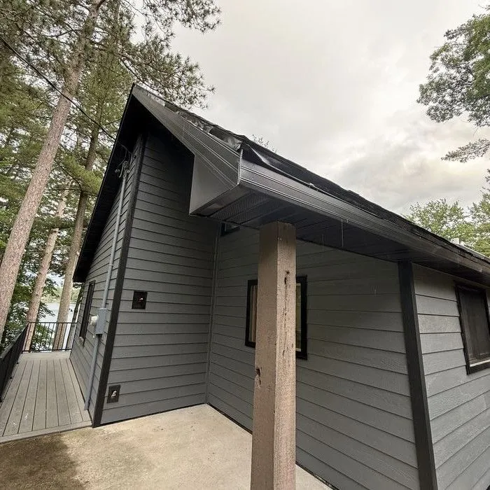 Covered entry with a wood post and new dark siding