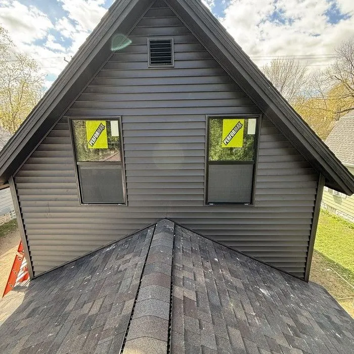 A gable with two windows in dark siding above the roof