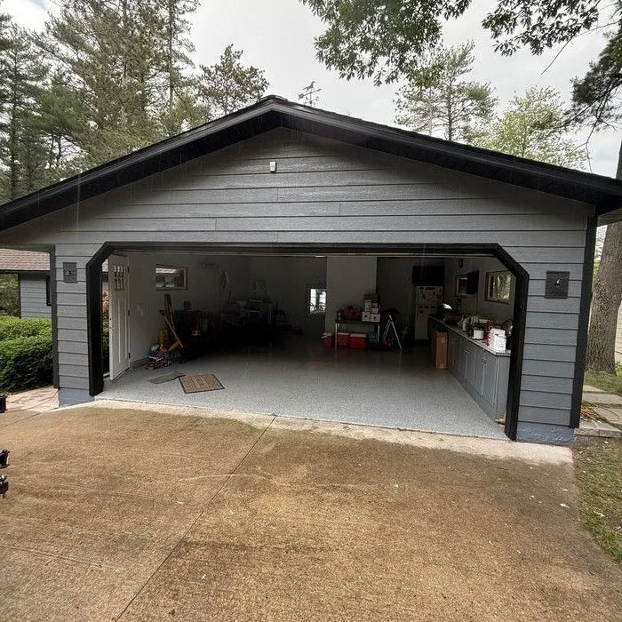 Front of the detached garage with the door open and new siding