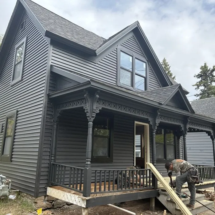 A Del's crew member working on the front porch steps of a grey Victorian house