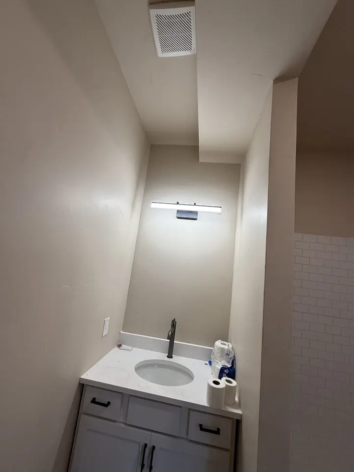 New bathroom vanity with a white top and dark faucet